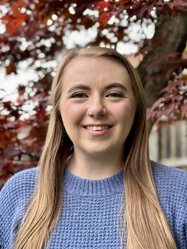 Headshot photo of Mikayla Mangrum outdoors with fall leaves behind her